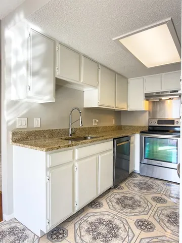 a kitchen with granite countertop a sink and a stove