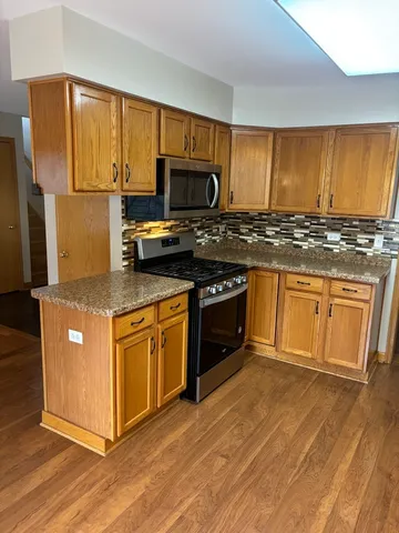 a kitchen with stainless steel appliances granite countertop a stove top oven a sink dishwasher and a microwave oven with cabinets
