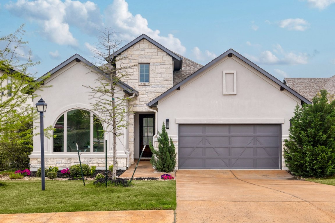 a view of a white house with a small yard plants and a large tree