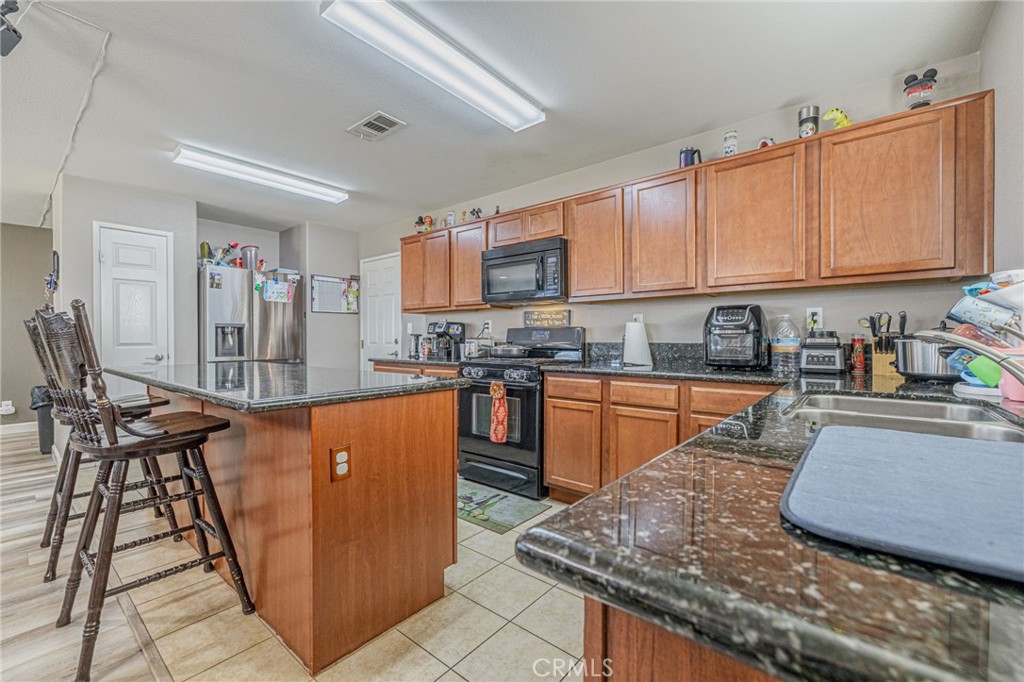 43128 Homestead Street Lancaster, CA 93535 - Photo 15 of 33 a kitchen with stainless steel appliances granite countertop a stove top oven a sink dishwasher and cabinets with wooden floor