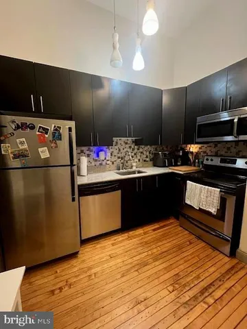 a kitchen with stainless steel appliances granite countertop a refrigerator a stove and a sink