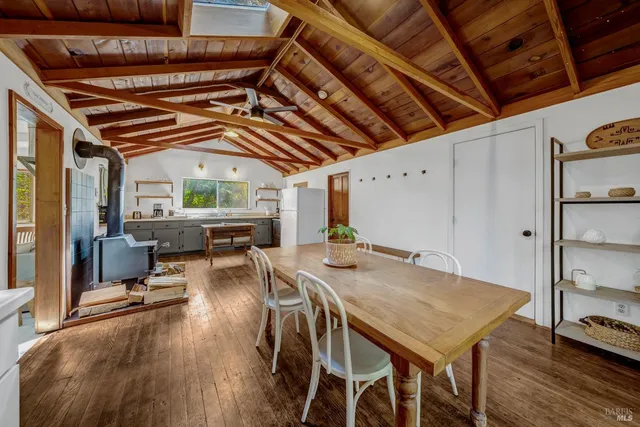 a kitchen with a refrigerator a sink dishwasher a stove and a dining table with wooden floor