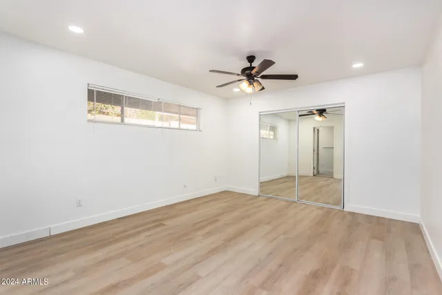 a view of empty room with wooden floor and ceiling fan