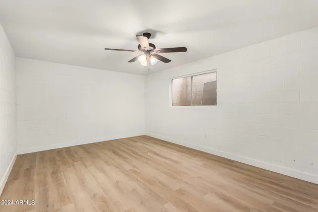 an empty room with a window and a ceiling fan