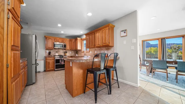 a kitchen with a refrigerator a stove top oven a sink a dining table and chairs