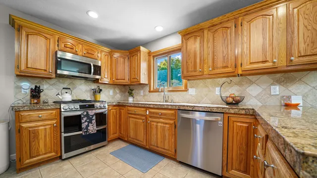 a kitchen with stainless steel appliances granite countertop wooden cabinets a sink and a stove