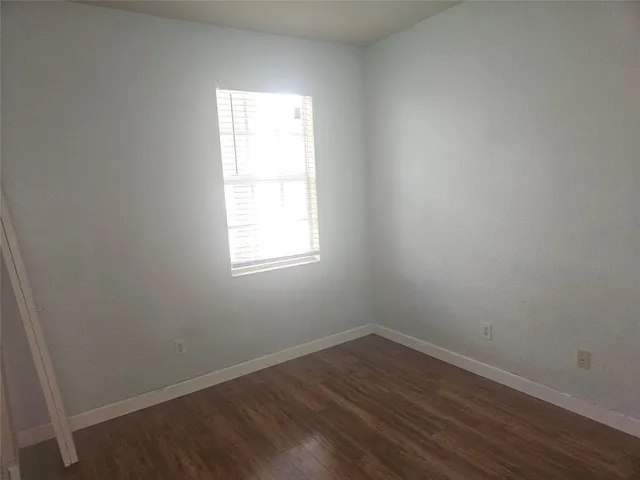 an empty room with wooden floor and window