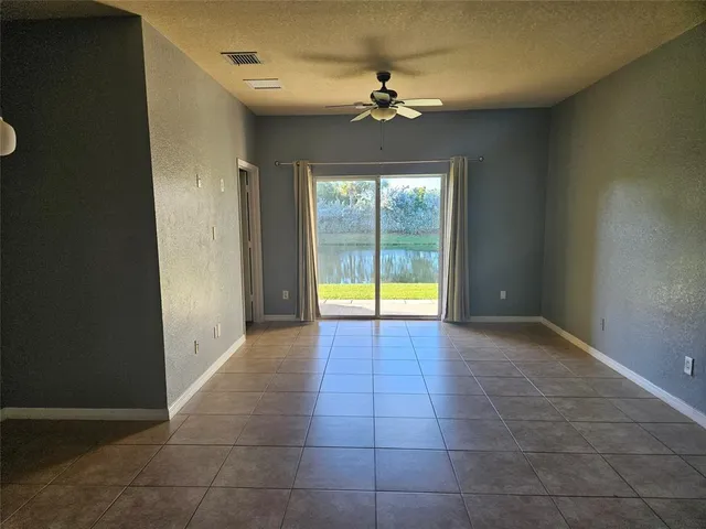 a view of an empty room with a chandelier fan and fire place