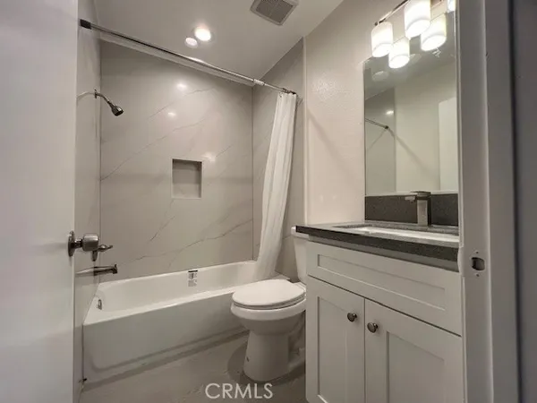 a bathroom with a bathtub shower sink vanity and toilet