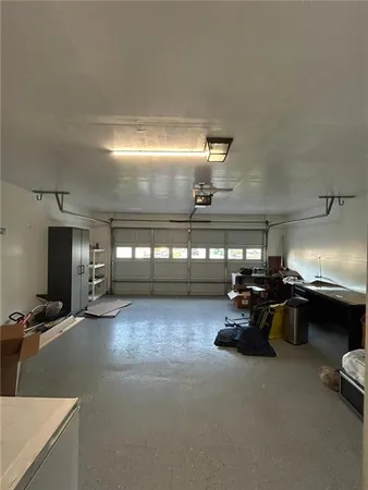 an empty room with a chandelier fan and windows