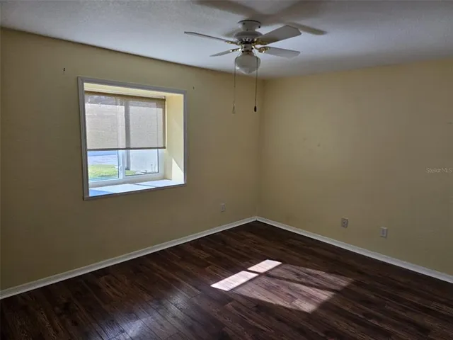 a view of an empty room with a window and wooden floor