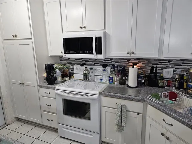 a kitchen with white cabinets and white appliances