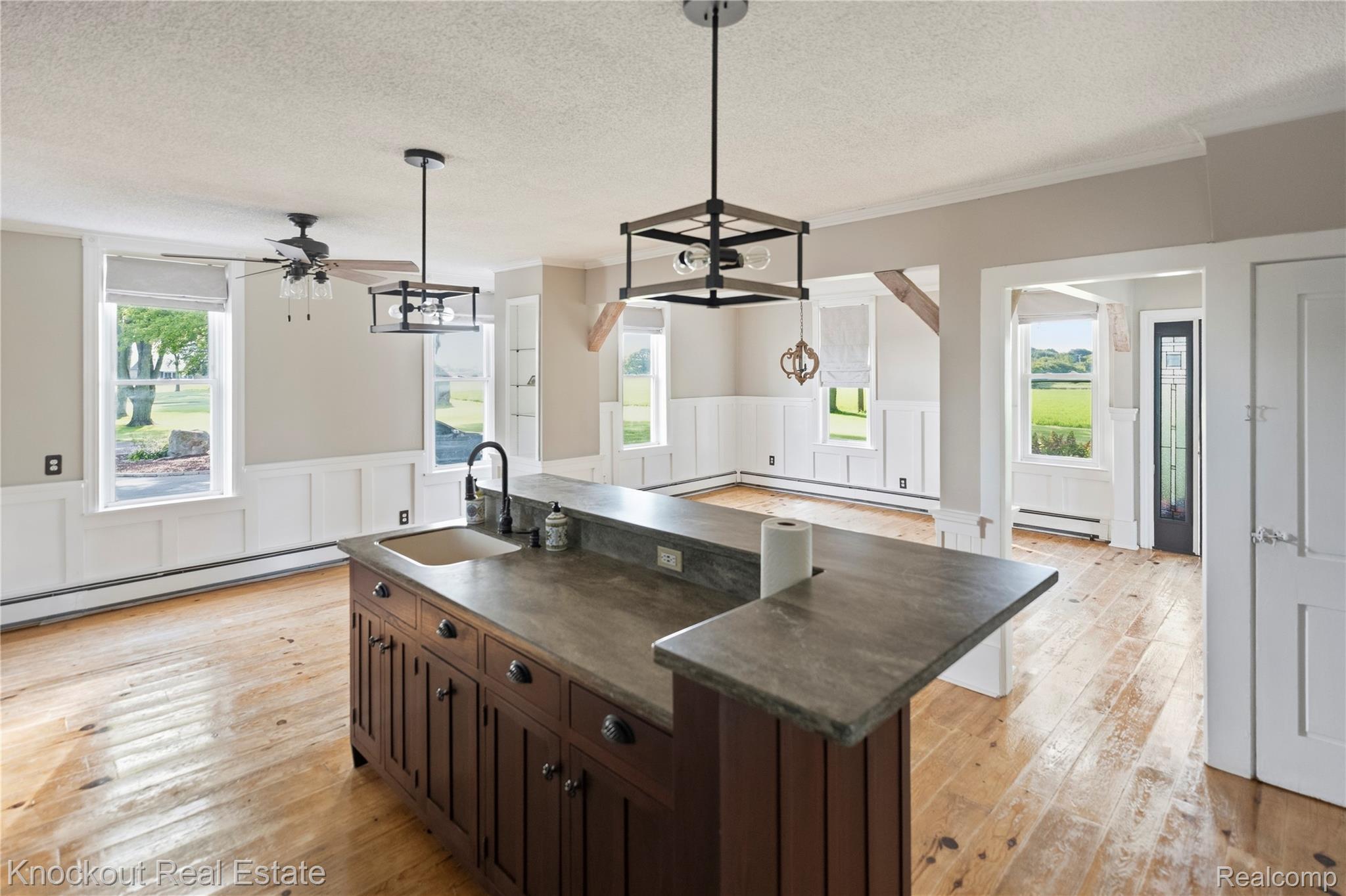 5750 Maple Road Frankenmuth, MI 48734 - Photo 11 of 60 Central kitchen island with an undermount sink, dark cabinetry, and stone-finish countertops