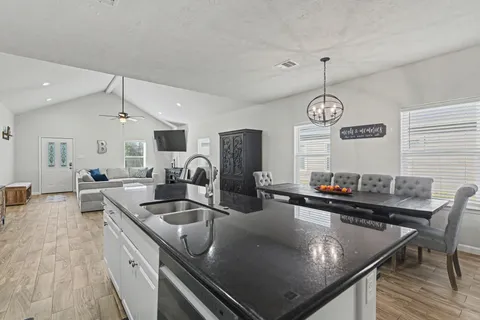 a kitchen with stainless steel appliances granite countertop a sink a stove and chairs