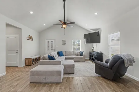 a living room with furniture a ceiling fan and a flat screen tv