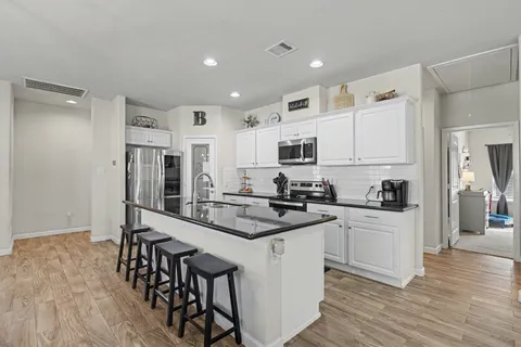 a kitchen with white cabinets and appliances