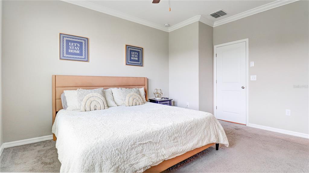 31632 Blue Passing Loop Wesley Chapel, FL 33545 - Photo 26 of 48 a bedroom with a large bed and a lamp on dresser