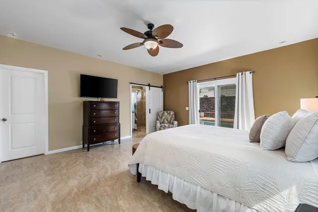 a bedroom with bed and a flat tv screen on dresser