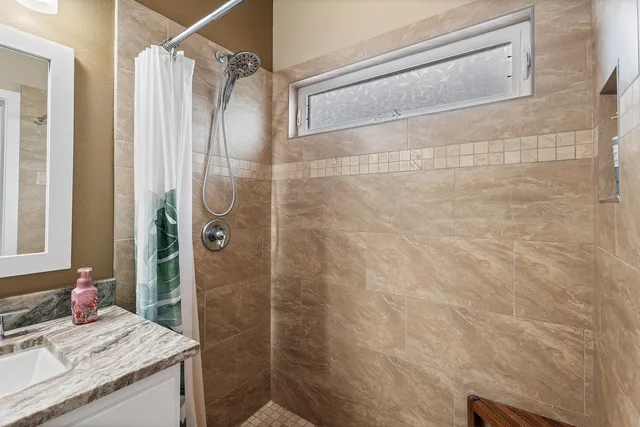 a bathroom with a granite countertop shower a sink and a mirror
