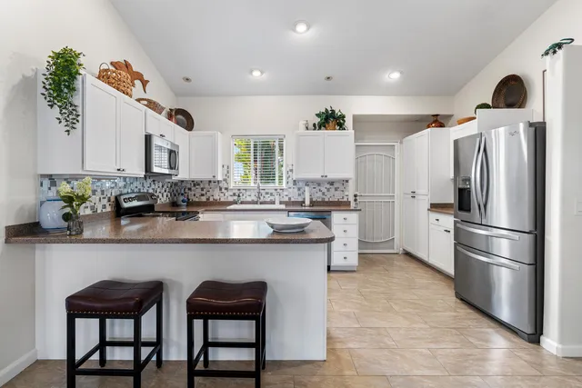a kitchen with stainless steel appliances granite countertop a sink a stove a refrigerator and cabinets