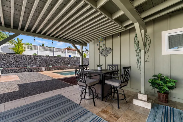 a patio with table and chairs with potted plants