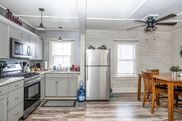 a kitchen with stainless steel appliances granite countertop a refrigerator a sink dishwasher a stove and white cabinets with wooden floor