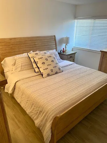 a bed sitting in a bedroom next to a window with a lamp