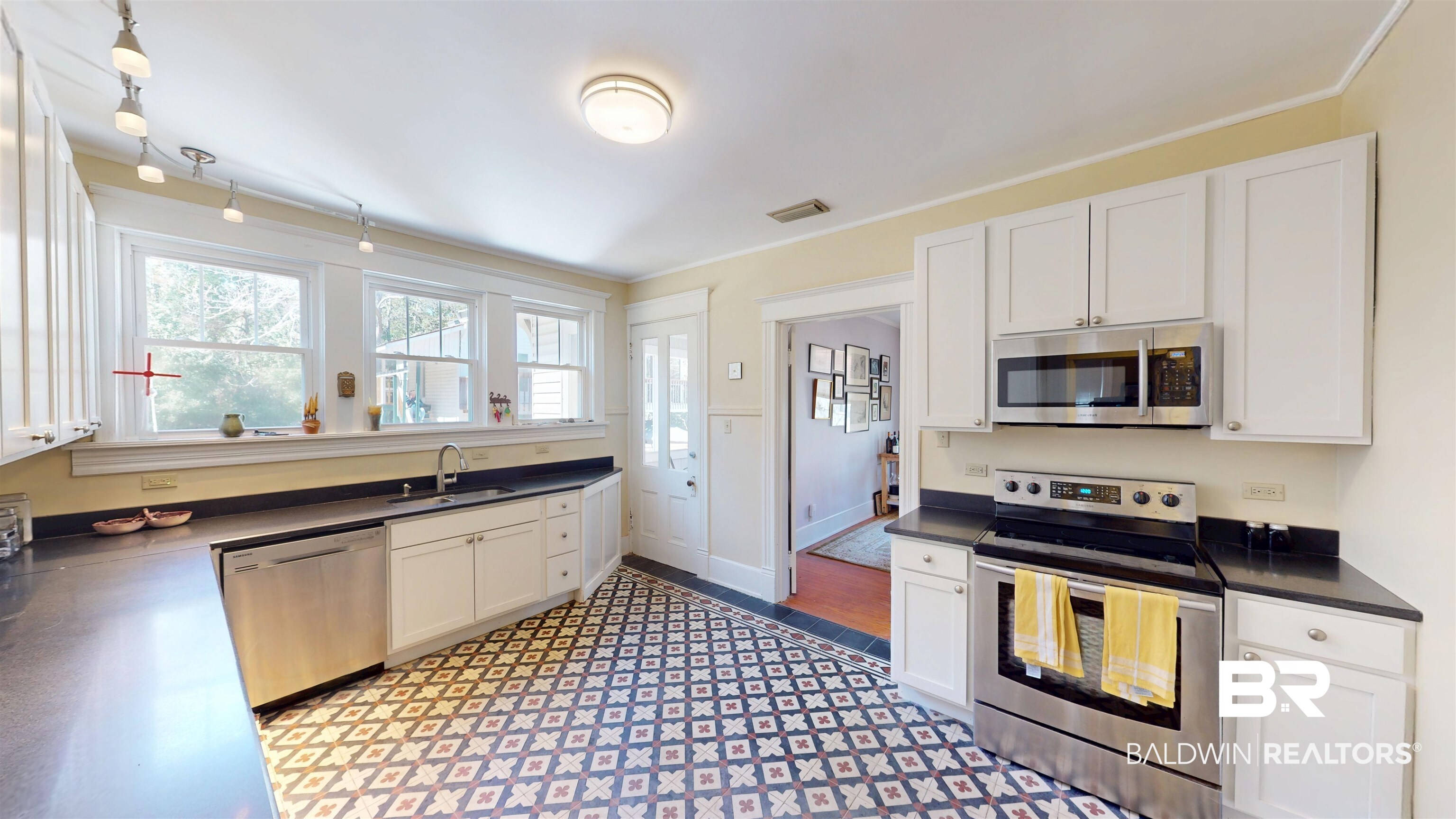 3220 Bayfront Road Mobile, AL 36605 - Photo 13 of 43 Kitchen with stainless steel appliances, dark countertops, white cabinetry, ornamental molding, and dark flooring