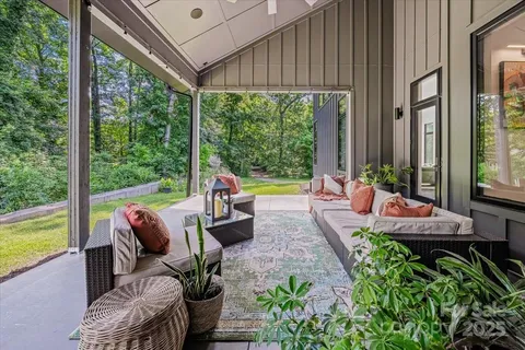 a view of a patio with couches chairs potted plants and floor to ceiling window yard