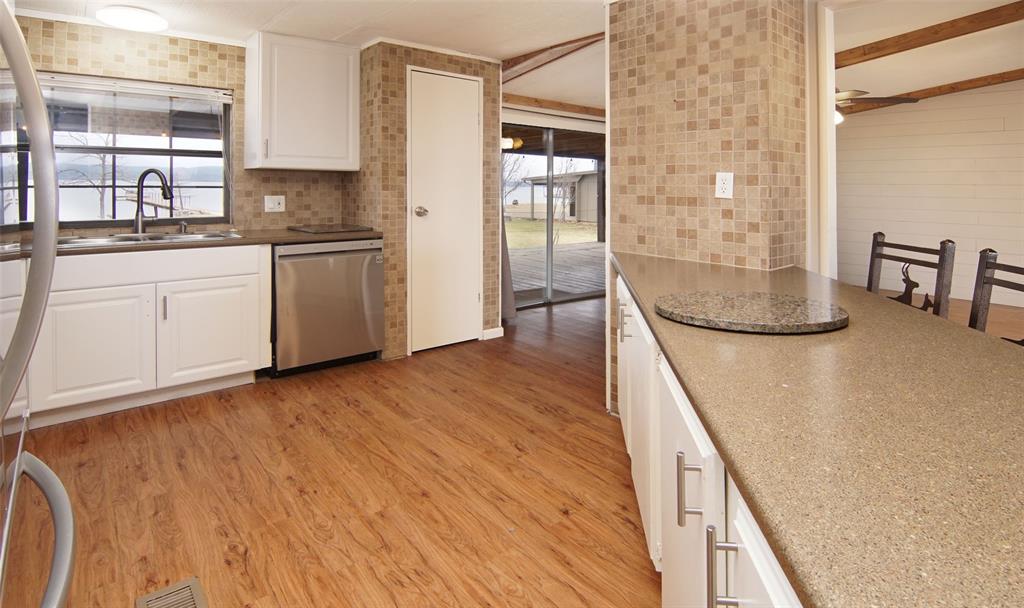 1059 Airport Road Graford, TX 76449 - Photo 11 of 35 a kitchen with stainless steel appliances granite countertop a sink and cabinets with wooden floor