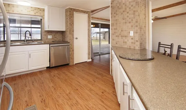 a kitchen with stainless steel appliances granite countertop a sink and cabinets with wooden floor
