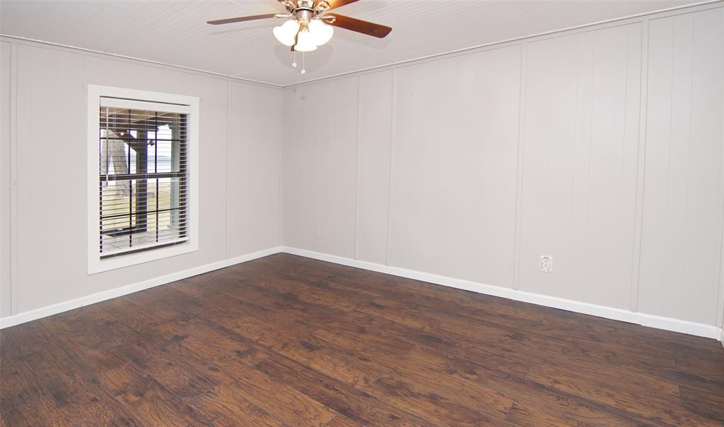 1059 Airport Road Graford, TX 76449 - Photo 19 of 35 an empty room with wooden floor chandelier fan and windows