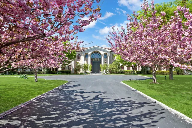 a front view of a house with garden and trees