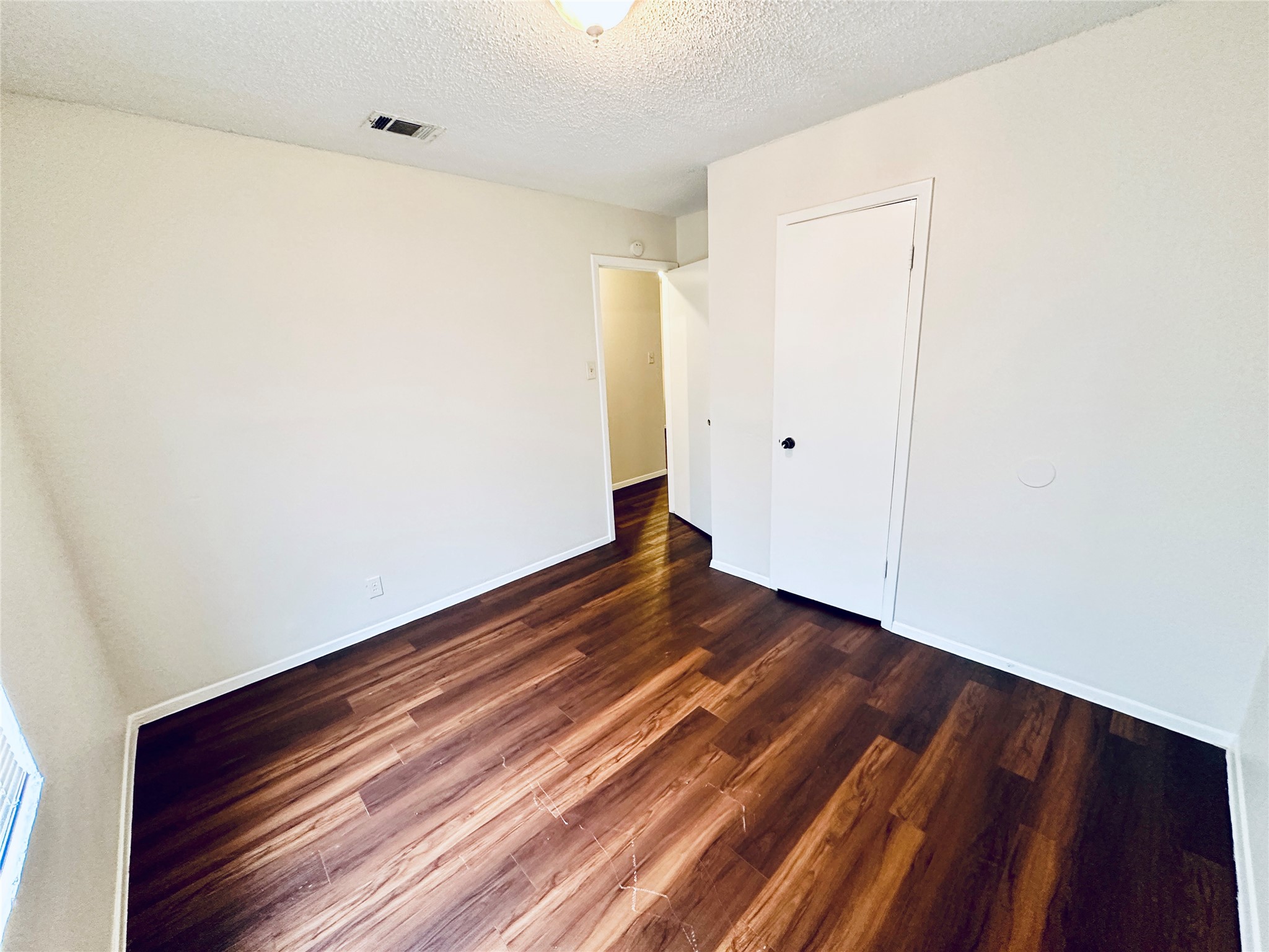 12505 Turtle Rock Road, Unit A Austin, TX 78729 - Photo 27 of 38 Rich hardwood-style flooring extends through this comfortable bedroom, offering a clean, inviting atmosphere.