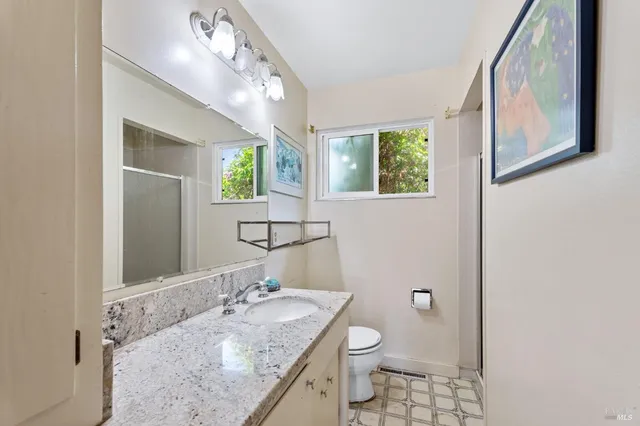 a bathroom with a granite countertop sink a mirror and a toilet