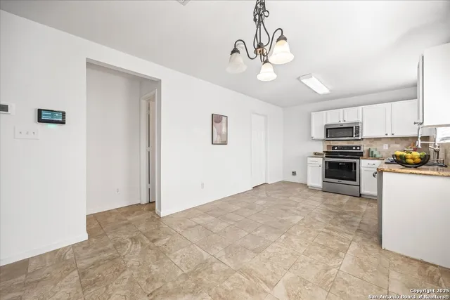 a kitchen with granite countertop white cabinets a sink a window and stainless steel appliances