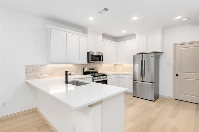 a kitchen with a sink a microwave a refrigerator and white cabinets