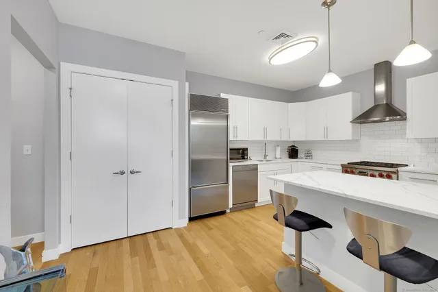 a kitchen with stainless steel appliances granite countertop a sink a stove and a refrigerator