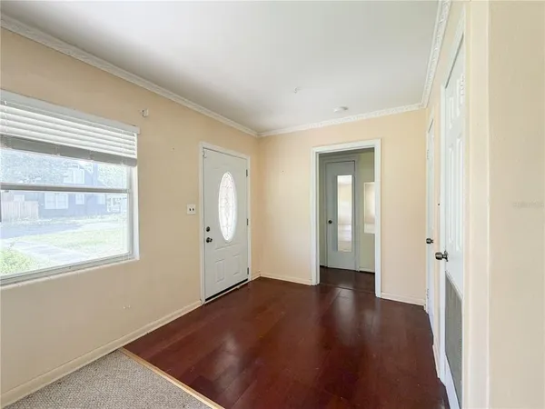 a view of an empty room with wooden floor and a window