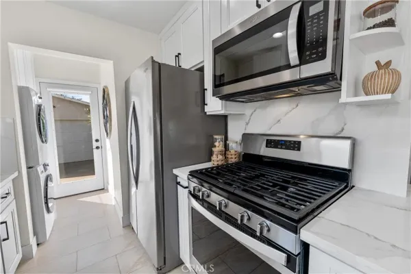 a kitchen with stainless steel appliances granite countertop a stove a sink a refrigerator a microwave a refrigerator and cabinets