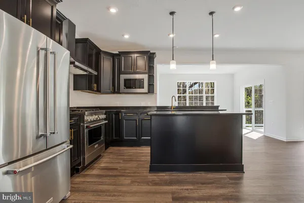 a view of kitchen with stainless steel appliances granite countertop a refrigerator a stove and a wooden floors