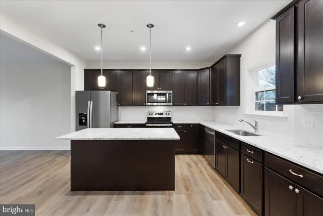 a kitchen with kitchen island stainless steel appliances a sink counter space and wooden floor