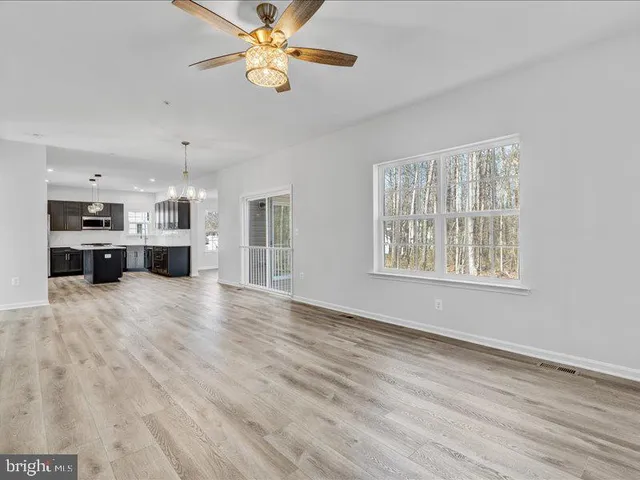 a view of an empty room with kitchen and window