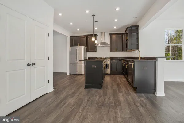 an open kitchen with wooden floor and stainless steel appliances