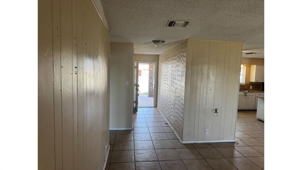 4004 Vicky Street Big Spring, TX 79720 - Photo 12 of 37 Corridor with tile patterned floors, a textured ceiling, and wooden walls