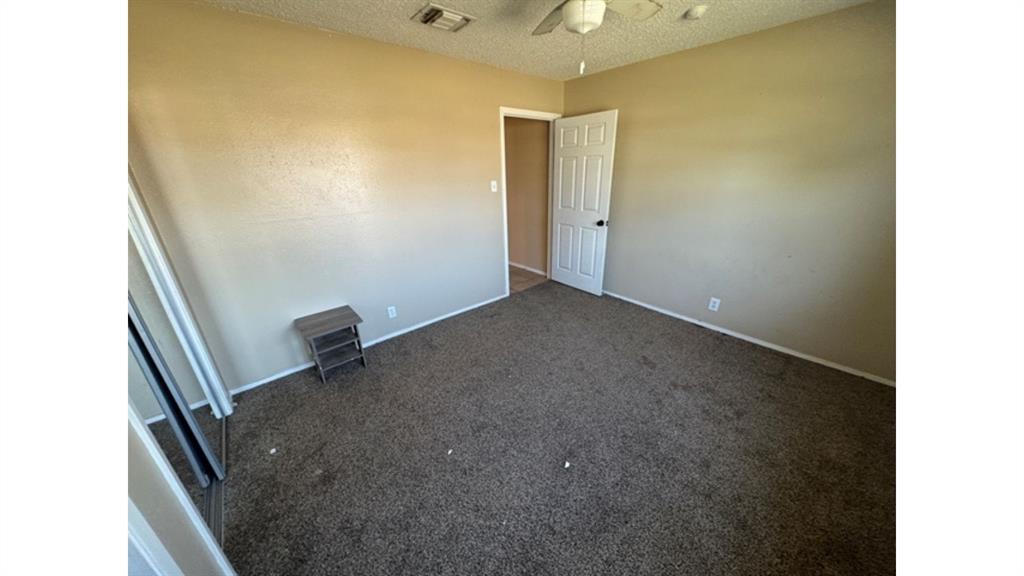 4004 Vicky Street Big Spring, TX 79720 - Photo 19 of 37 Spare room with a textured ceiling, a ceiling fan, and dark carpet