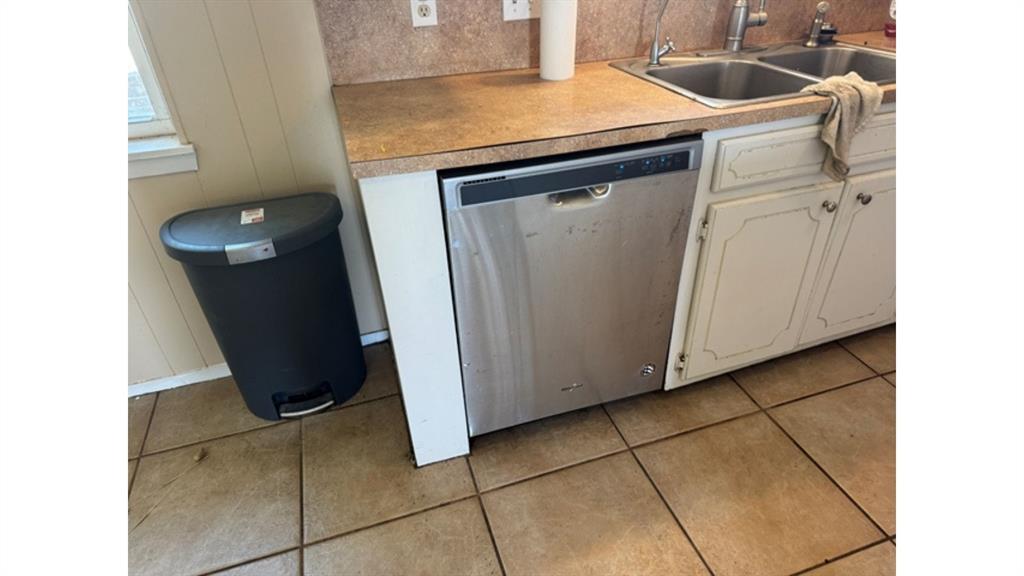 4004 Vicky Street Big Spring, TX 79720 - Photo 30 of 37 Kitchen featuring dishwasher, light countertops, light tile patterned floors, and white cabinets