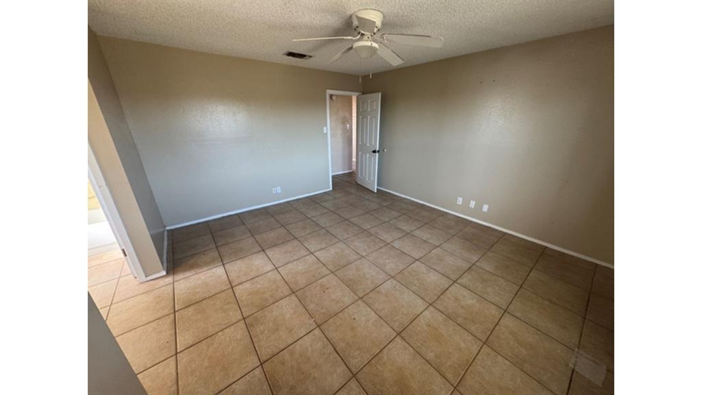 4004 Vicky Street Big Spring, TX 79720 - Photo 3 of 37 Empty room with a textured ceiling, ceiling fan, and tile patterned floors