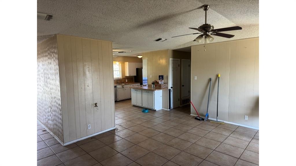 4004 Vicky Street Big Spring, TX 79720 - Photo 32 of 37 Spare room featuring a textured ceiling, wooden walls, a ceiling fan, and dark tile patterned floors