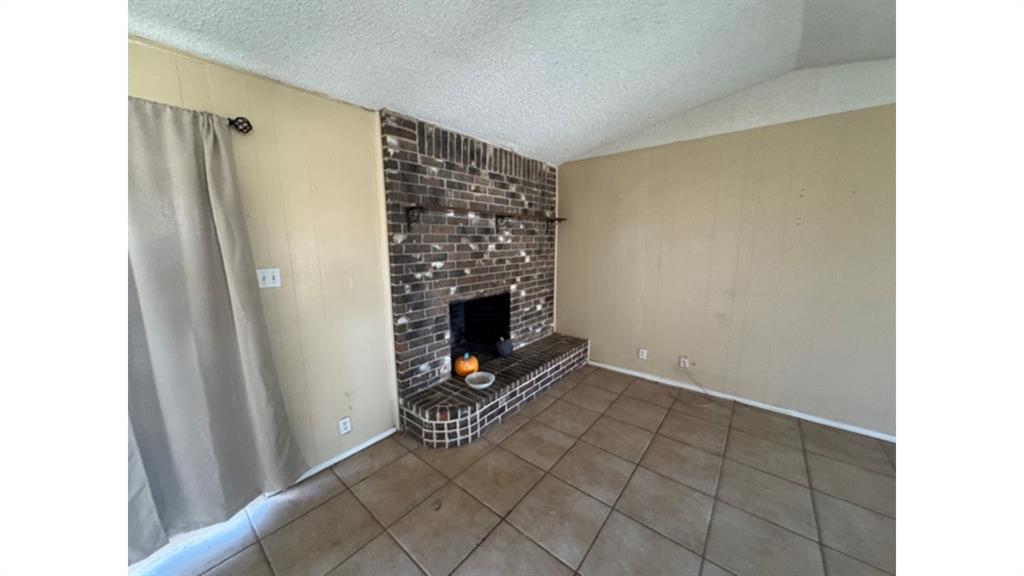 4004 Vicky Street Big Spring, TX 79720 - Photo 5 of 37 Unfurnished living room featuring wooden walls, a fireplace, and tile patterned flooring